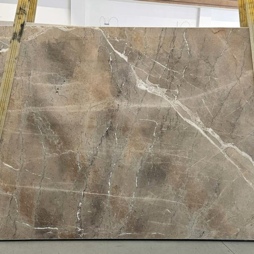Noisette Fleury marmorplade — varm grå-beige og taupe baggrund med subtile bølgende årer i hvid og mørkegrå poleret finish