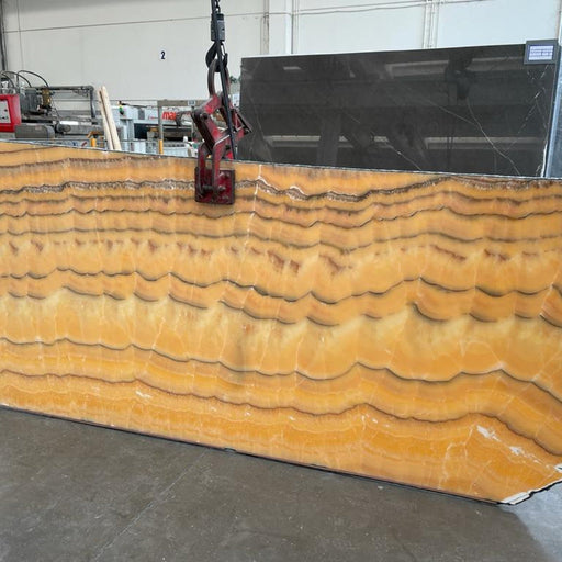 Onice Arancio onyx plade — intens orange og gyldengul baggrund med tætte parallelle bølgende bånd i hvid og brun poleret finish