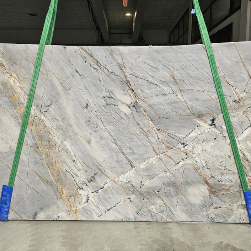 Ijen Blue quartziteplade — lys grå-blå baggrund med dramatiske gyldne sorte og rustfarvede vulkanske årer poleret finish