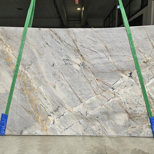 Ijen Blue quartziteplade — lys grå-blå baggrund med dramatiske gyldne sorte og rustfarvede vulkanske årer poleret finish