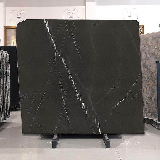 Pietra Grey Graphite marmorplade — dyb mørk grafitgrå baggrund med fine diagonale hvide årer poleret finish